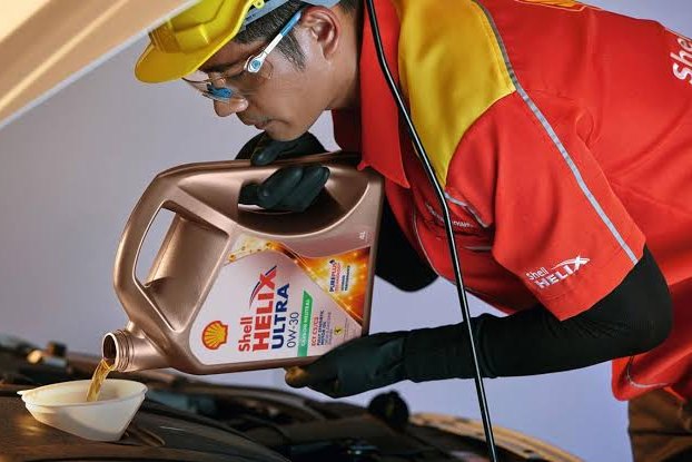 Shell Helix engine oil being poured during a service